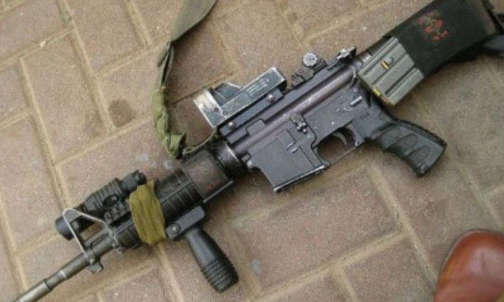 An image of an AR-15 lying down on a brick pavement.