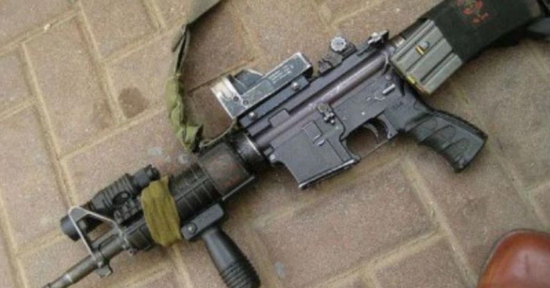 An image of an AR-15 lying down on a brick pavement.