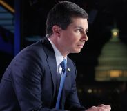 Pete Buttigieg, arched forward, sits during a Fox News broadcast while wearing a suit and blue tie.