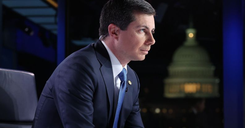 Pete Buttigieg, arched forward, sits during a Fox News broadcast while wearing a suit and blue tie.