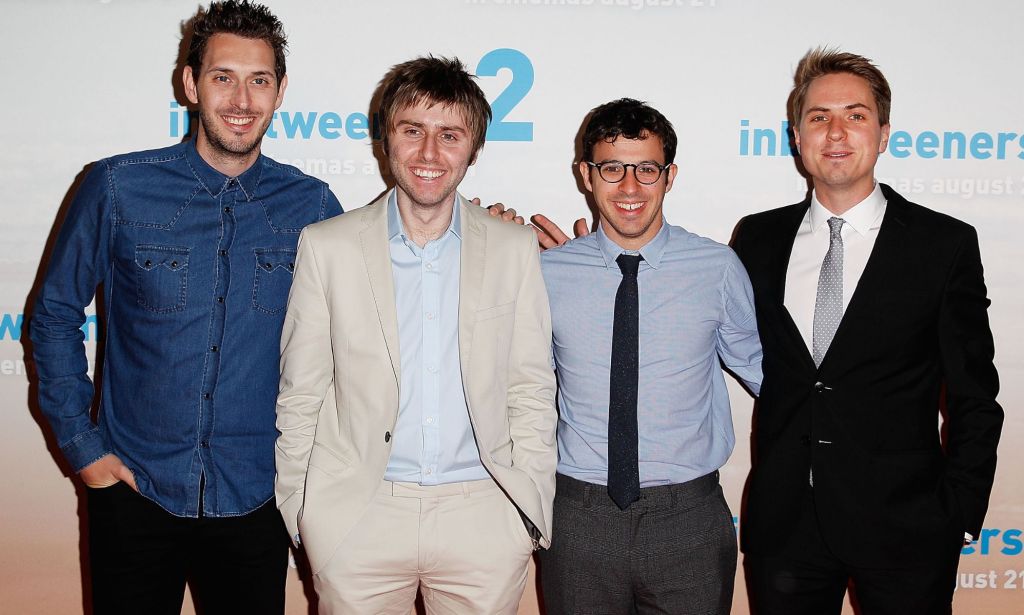 Members of The Inbetweeners cast smile against a white backdrop.