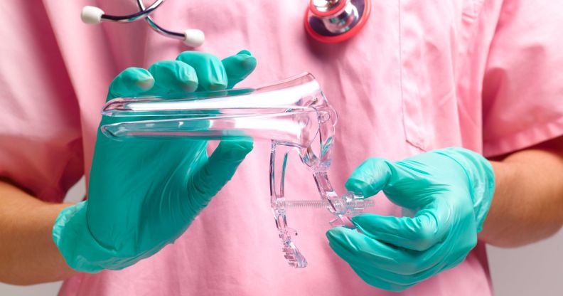 A doctor wearing a pink scrubs is holding equipment used in a cervix screening test