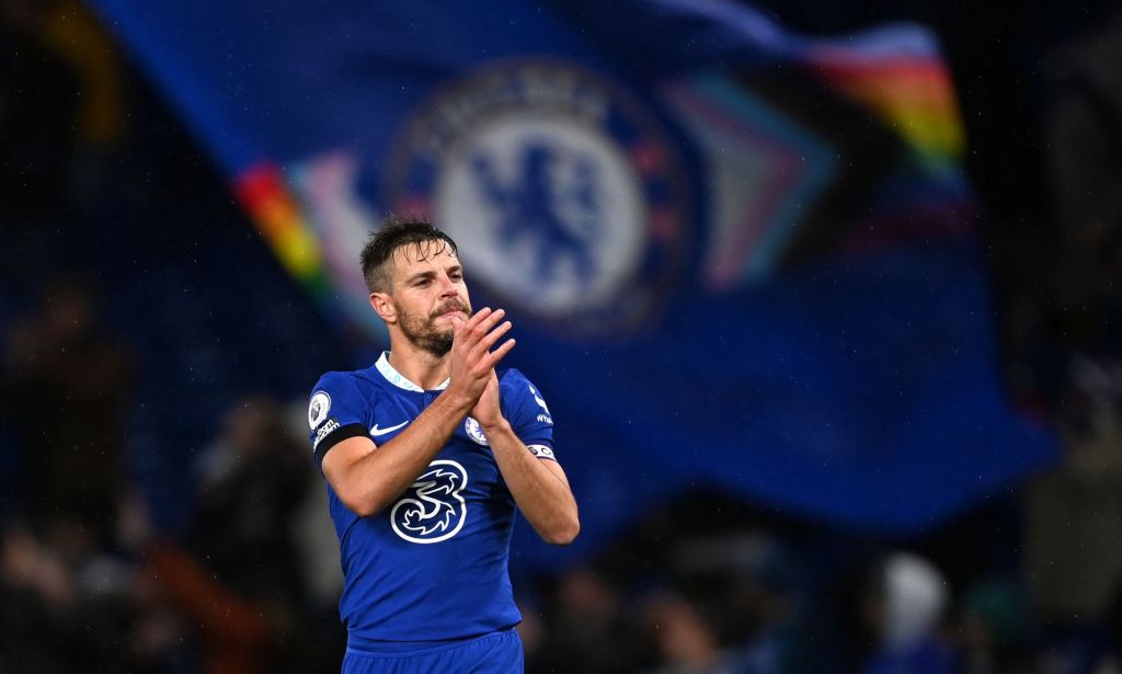 Chelsea player Cesar Azpilicueta claps during the end of a match while a Pride Chelsea flag waves in the background.
