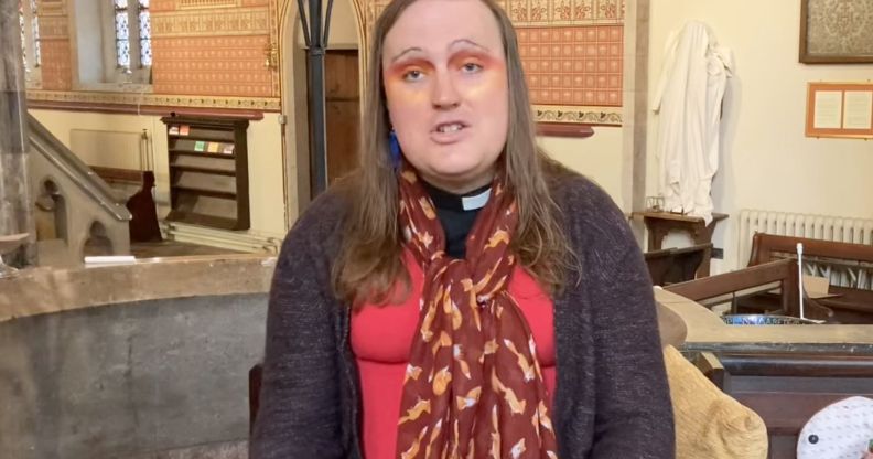 Bingo Allison, a non-binary, genderqueer Church of England priest, wears a red top, sweater and scarf while they speak about religion and Trans Day of Visibility