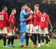 Manchester United players, wearing red football uniforms, gather around each other
