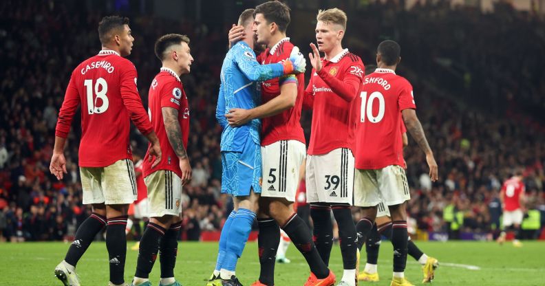 Manchester United players, wearing red football uniforms, gather around each other