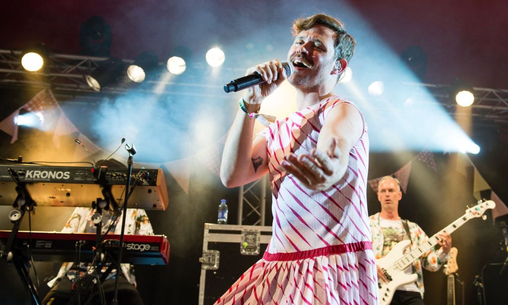 Will Young wears a red and white striped outfit as he sings into a microphone during a performance at Glastonbury