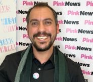 Leng Montgomery wears a dark top and green plaid scarf as he smiles at the camera after winning the Trans in the City trans corporate champion award for his work on diversity, equity and inclusion
