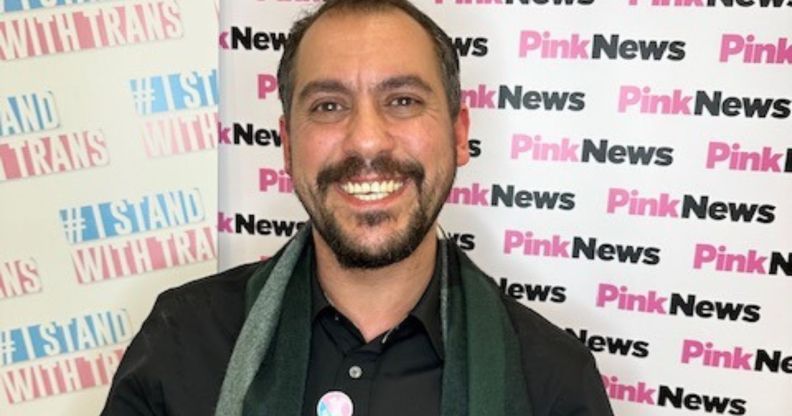 Leng Montgomery wears a dark top and green plaid scarf as he smiles at the camera after winning the Trans in the City trans corporate champion award for his work on diversity, equity and inclusion