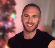 An Instagram photo of gay porn actor Shawn Paul Bertrand Jr wearing a black t-shirt sitting in front of a Christmas tree