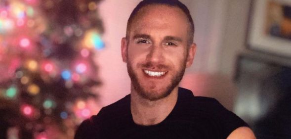 An Instagram photo of gay porn actor Shawn Paul Bertrand Jr wearing a black t-shirt sitting in front of a Christmas tree