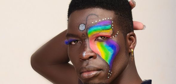 A photo shows a close-up of Kenyan LGBTQ+ activist Edwin Chiloba wearing rainbow and glitter makeup with his hand behind his head