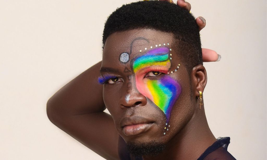 A photo shows a close-up of Kenyan LGBTQ+ activist Edwin Chiloba wearing rainbow and glitter makeup with his hand behind his head