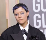 Actor Emma D'Arcy on the Golden Globes red carpet wearing a black suit with cropped purple hair.
