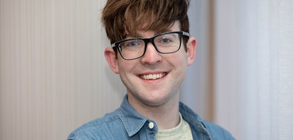 A close-up photo of Galway City councillor Owen Hanley wearing a grey t-shirt and blue shirt wearing glasses and smiling to the camera