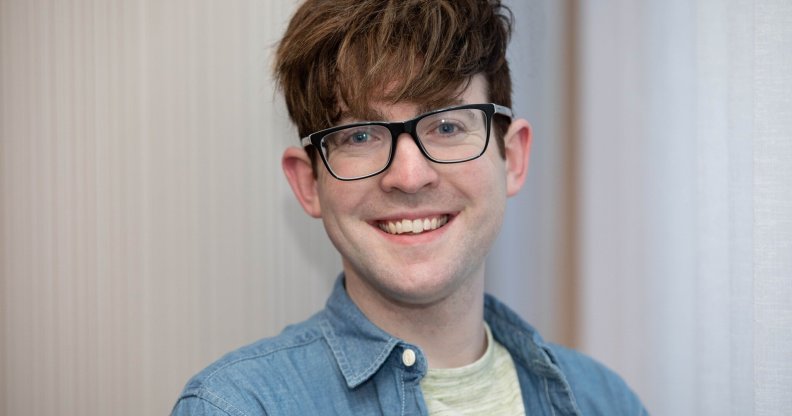 A close-up photo of Galway City councillor Owen Hanley wearing a grey t-shirt and blue shirt wearing glasses and smiling to the camera