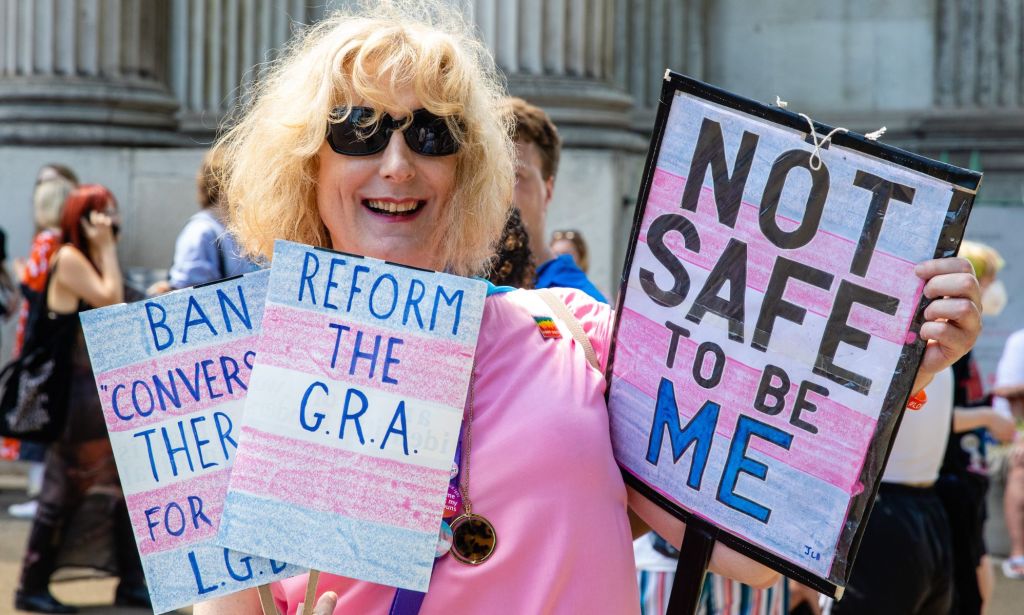 A protestor holds up several cards, with one reading 'reform the GRA.'