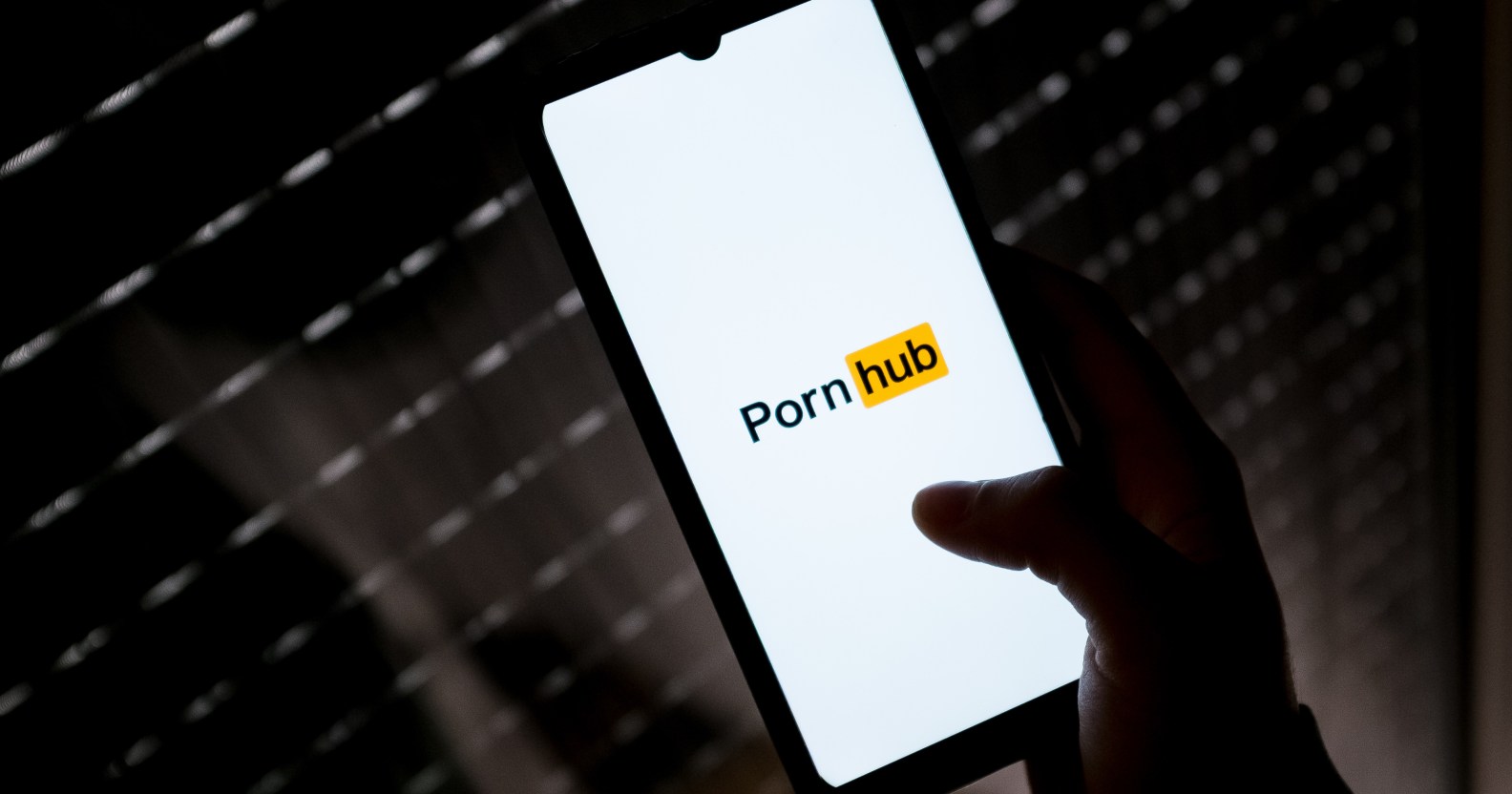 A photo shows a smartphone being held with the "PornHub" logo on a white background