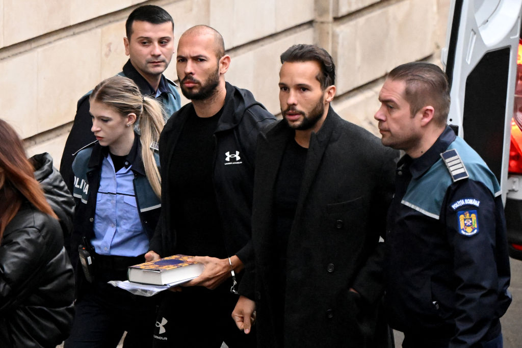 A photo shows controverisal influencer Andrew Tate and his brother Tristan Tate dressed in black arrive handcuffed and escorted by police at a courthouse in Bucharest