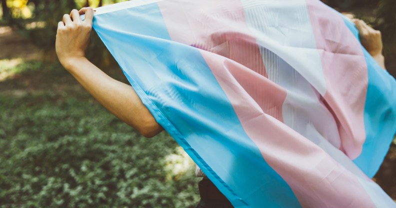 Close-up of a person walking while holding a transgender Pride flag behind their back