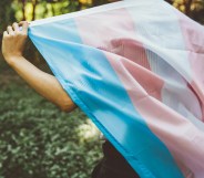 Close-up of a person walking while holding a transgender Pride flag behind their back