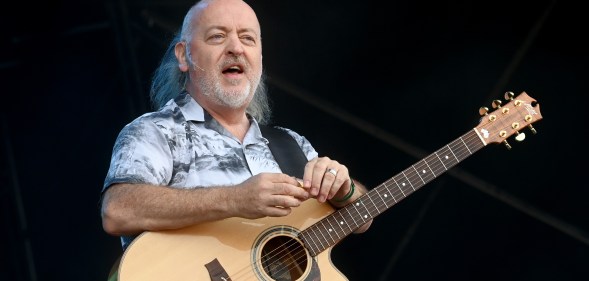 Comedian Bill Bailey standing with a guitar