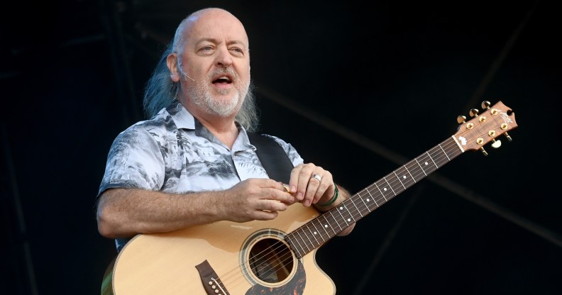 Comedian Bill Bailey standing with a guitar