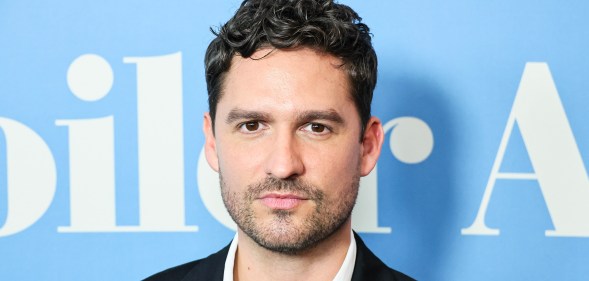 Knock at the Cabin star Ben Aldridge poses in front of a blue background
