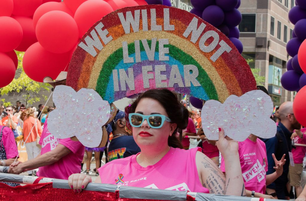 A woman stands under an elaborate, rainbow gay pride banner with the text "We will not live in fear", during the 46th Lesbian, Gay, Bisexual and Transgender Pride March, New York City,