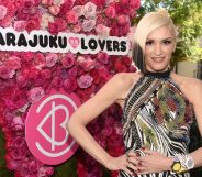 Pop star Gwen Stefani stands in front of the logo for her perfume collection Harajuku Lovers, against a backdrop of pink roses.