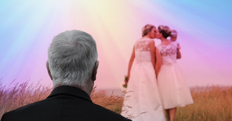 Two women kiss in wedding gowns while a man looks on