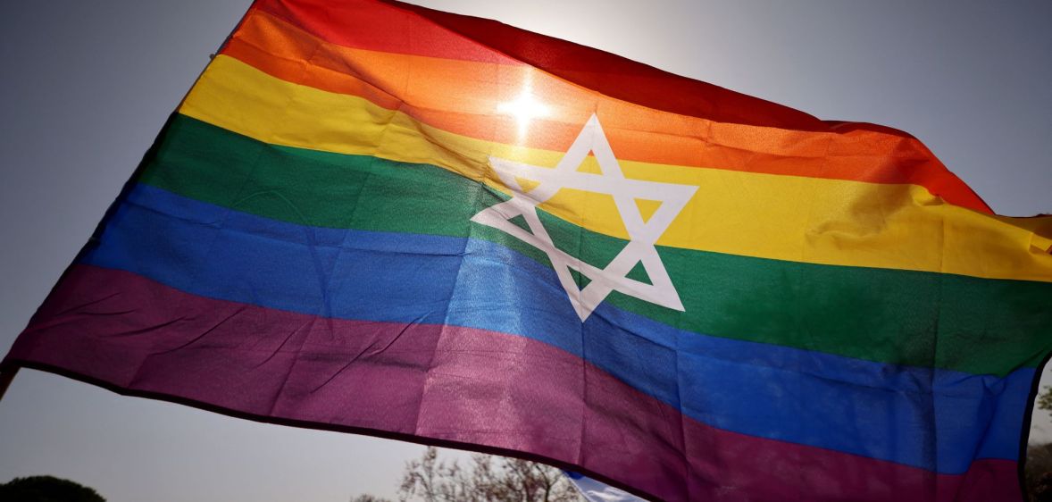 A photo of an Israel flag with the LGBTQ+ stripes during a Pride march.