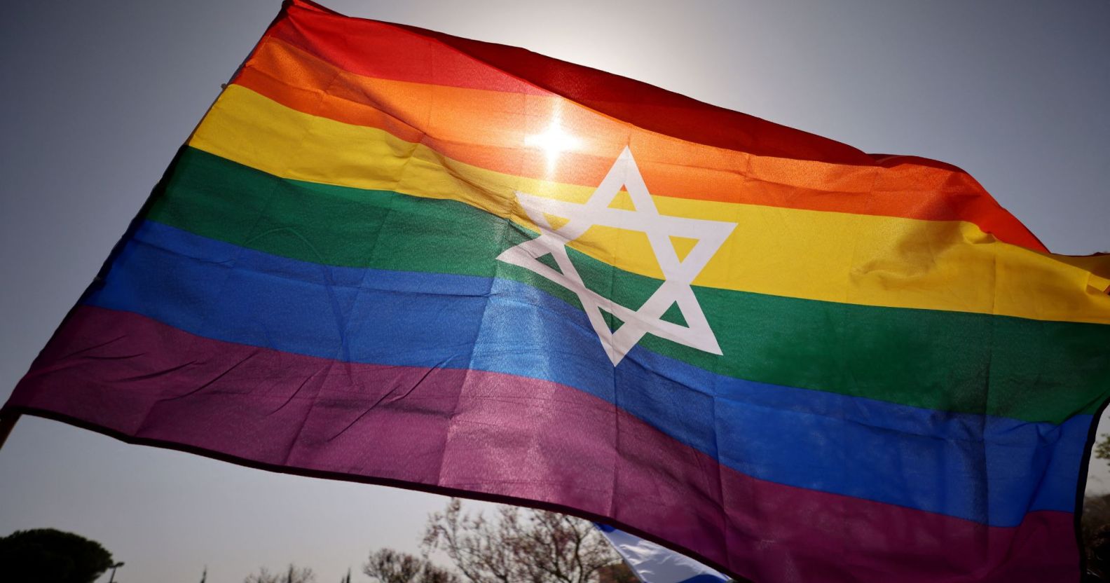 A photo of an Israel flag with the LGBTQ+ stripes during a Pride march.