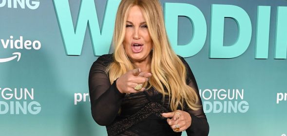 Jennifer Coolidge wearing a black dress at the Shotgun Wedding premiere, pointing at the camera with her mouth open.