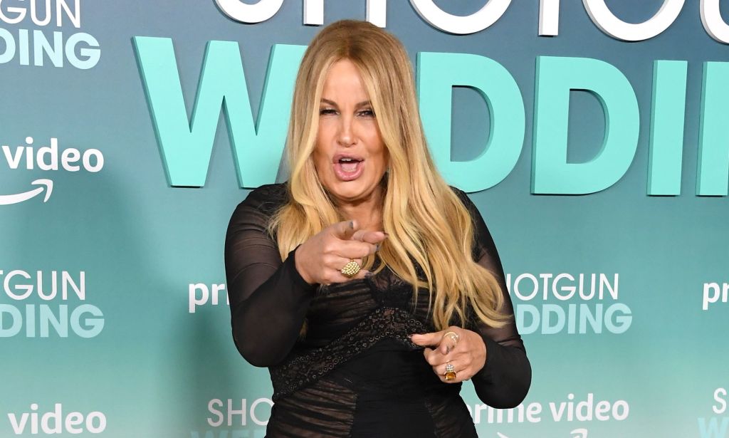 Jennifer Coolidge wearing a black dress at the Shotgun Wedding premiere, pointing at the camera with her mouth open.