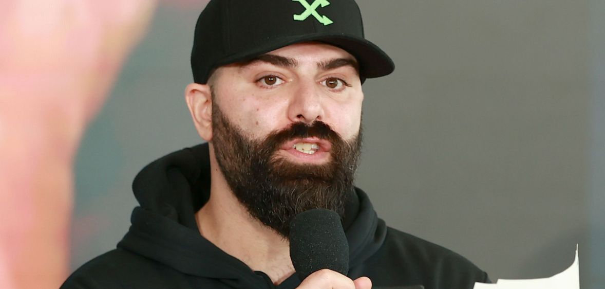 Daniel M Keem, known as Keemstar, speaks into a microphone while wearing a baseball cap and black jumper.