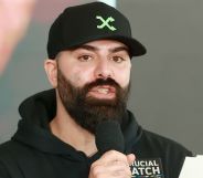 Daniel M Keem, known as Keemstar, speaks into a microphone while wearing a baseball cap and black jumper.
