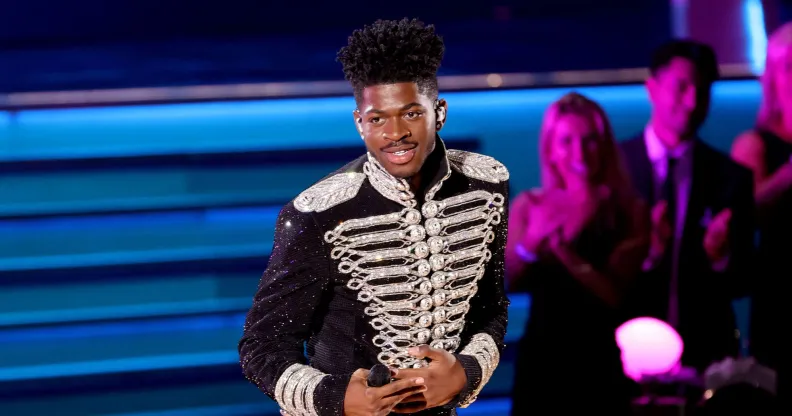 Lil Nas X performs at the 2022 Grammy Awards in a black and silver jacket.