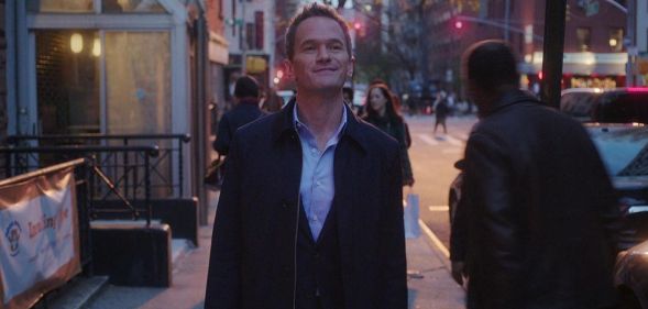 Neil Patrick Harris in Netflix series Uncoupled. The actor is shown in a still image walking down a street wearing a jacket as night falls.