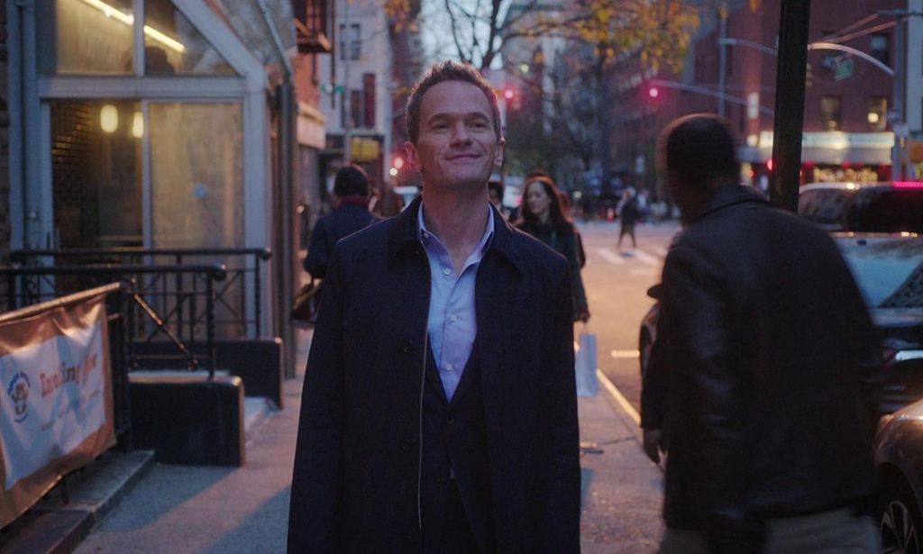 Neil Patrick Harris in Netflix series Uncoupled. The actor is shown in a still image walking down a street wearing a jacket as night falls.