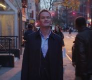 Neil Patrick Harris in Netflix series Uncoupled. The actor is shown in a still image walking down a street wearing a jacket as night falls.