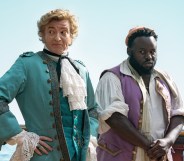 A still from HBO's Our Flag Means Death showing actors Rhys Darby and Samson Kayo dressed as pirates and standing on a ship