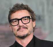 A close-up screenshot of actor Pedro Pascal wearing a black suit and glasses