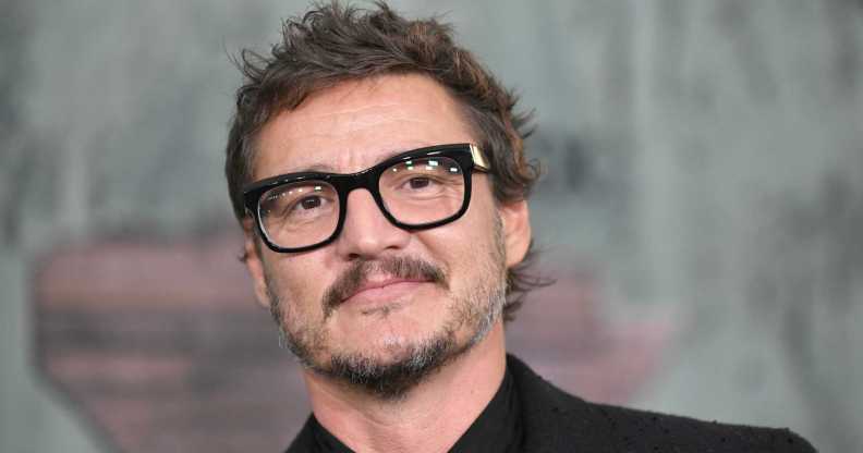 A close-up screenshot of actor Pedro Pascal wearing a black suit and glasses