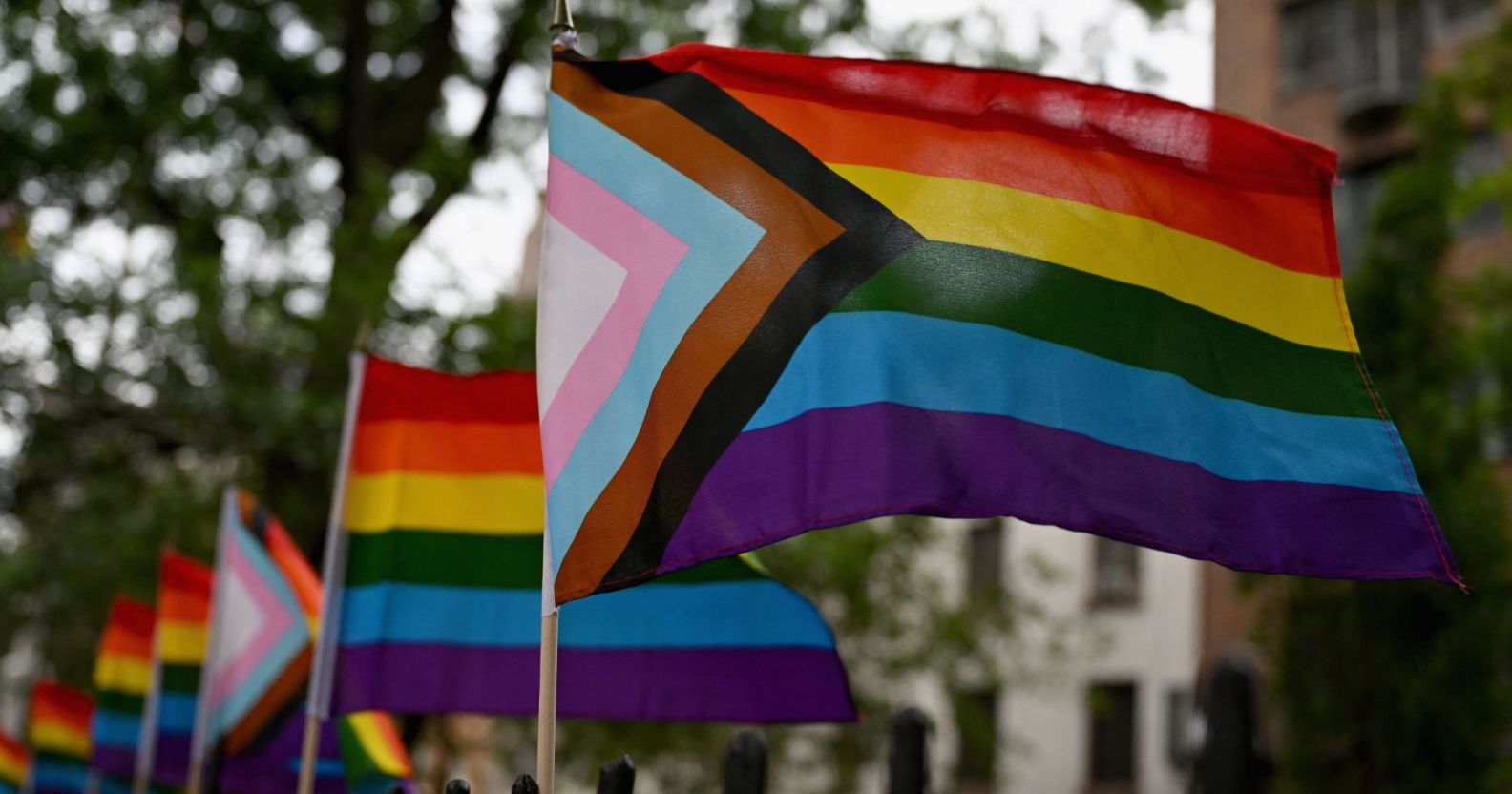 LGBTQ+ progress flags wave in an American street.