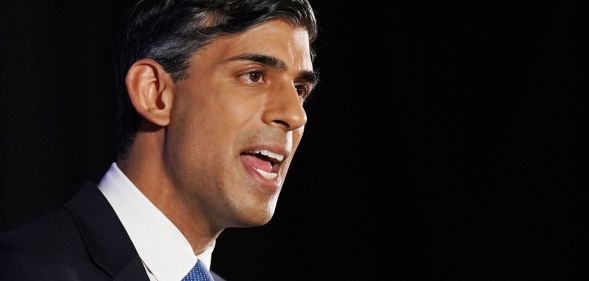 Rishi Suunak speaks infront of a black background.