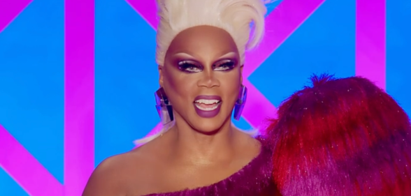 RuPaul judging Drag Race UK season 4 in a blonde wig and red and pink dress