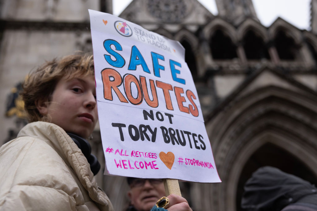 A 'Stand up to Racism' campaigner outside the Royal Courts of Justice holding a sign that reads "safe routes not Tory brutes" on December 19, 2022 in London, England. 