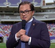 Bowen Yang dressed as George Santos during an SNL skit infront of a greenscreen of an NFL football field.