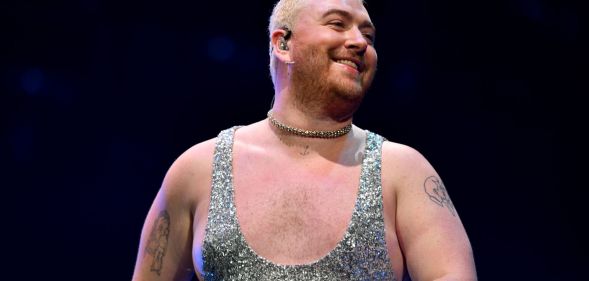 Sam Smith smiling while performing at the 2022 Jingle Bell Ball wearing a silver glittery jumpsuit